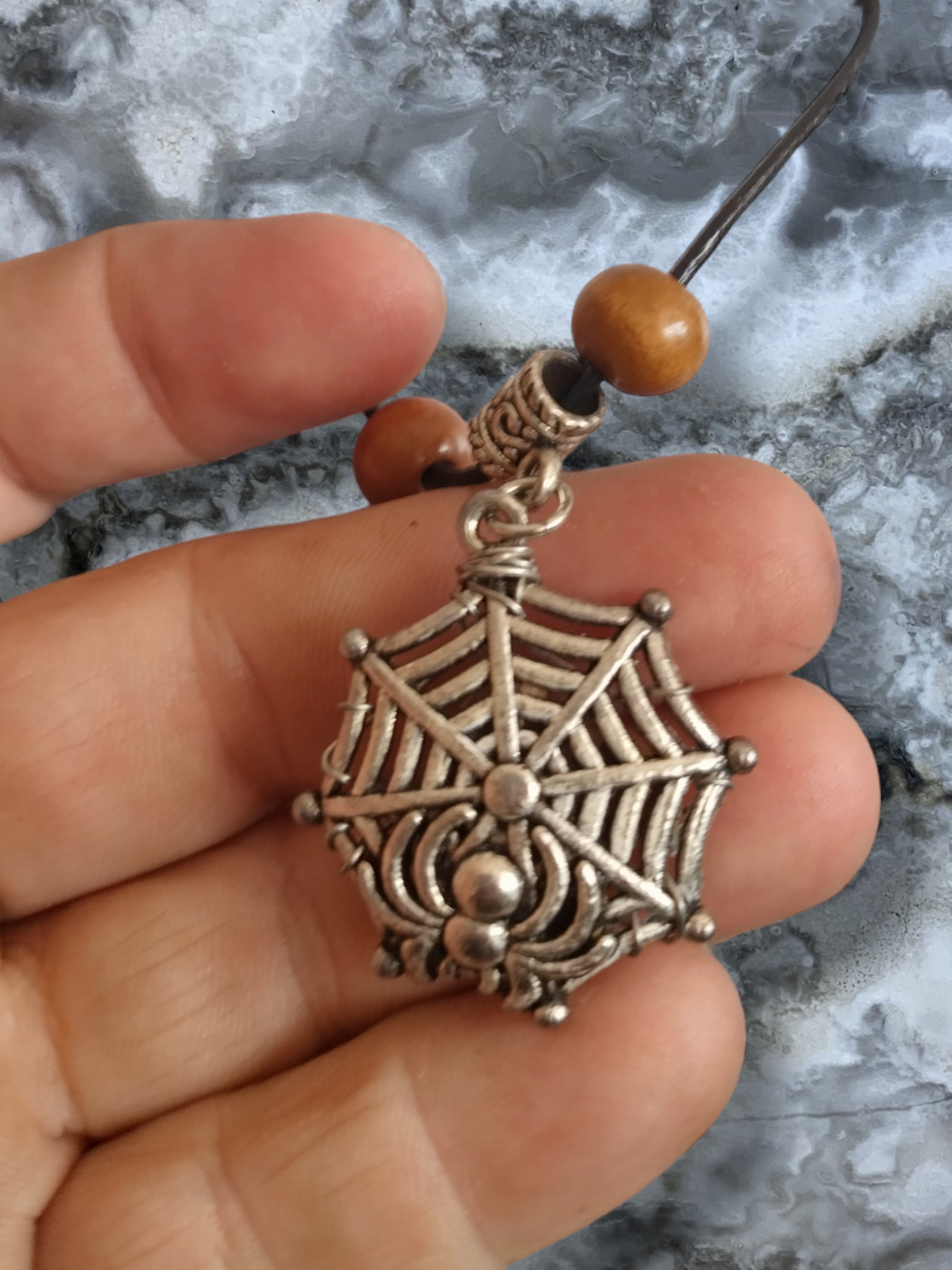 Petrified wood in a spider web on an adjustable leather cord necklace.