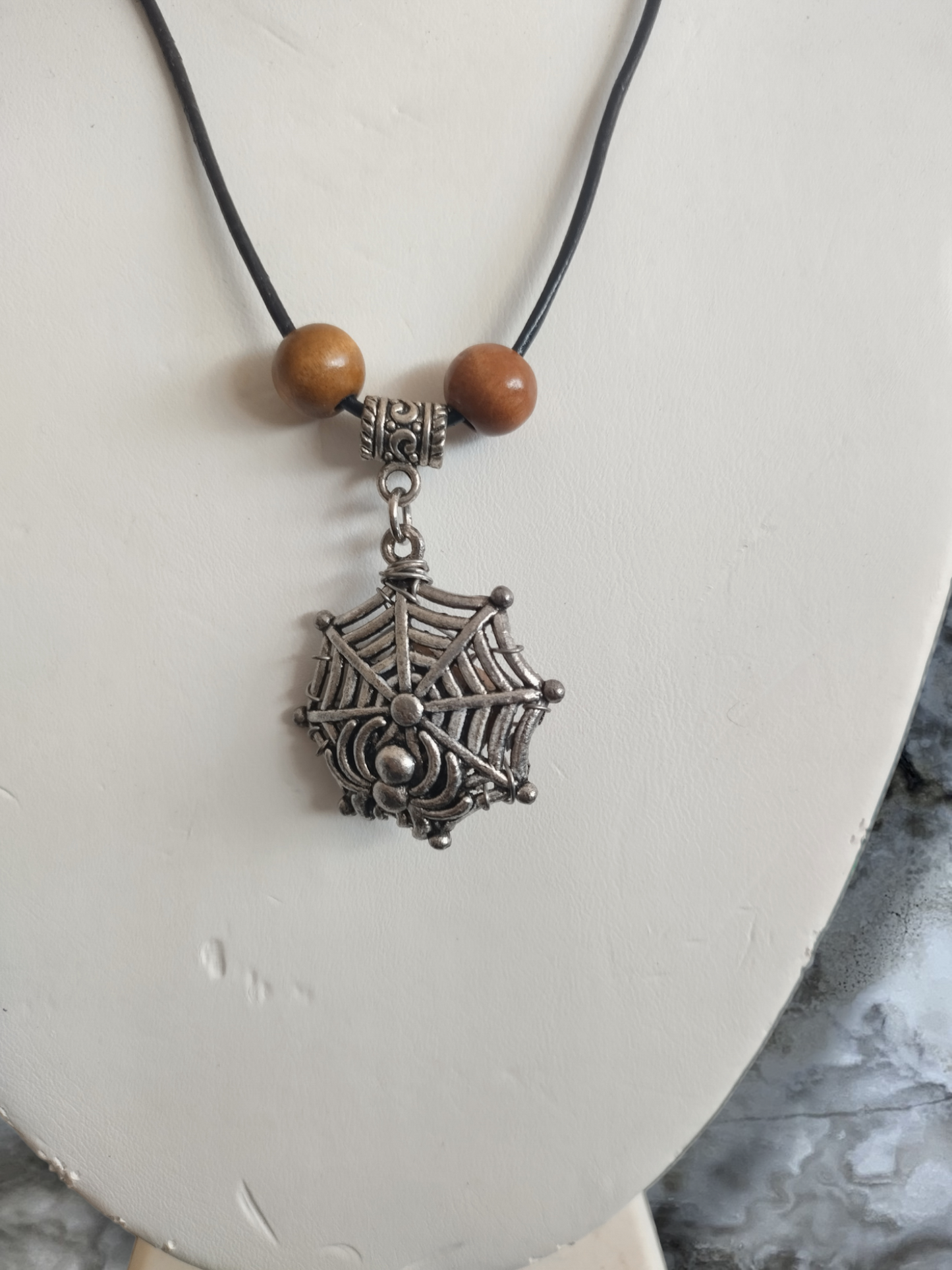 Petrified wood in a spider web on an adjustable leather cord necklace.